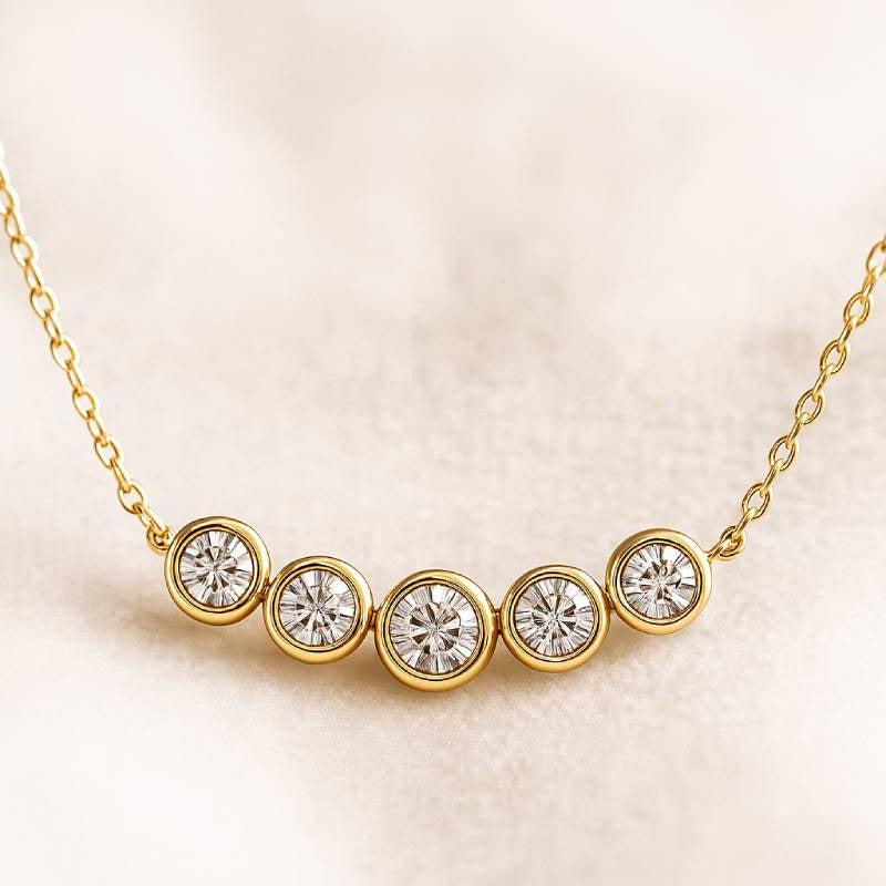 Gold necklace with five diamond stones on a light beige background