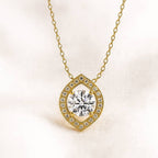 Gold necklace with a diamond pendant on a light pink background