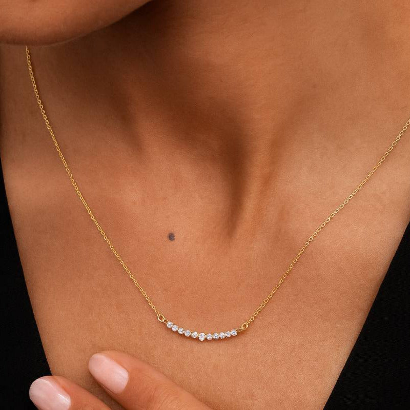Gold necklace with small pearls worn by a person against a black background