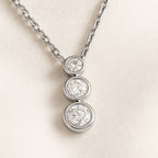 necklace with three round diamonds on a light beige background