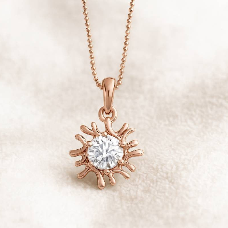 Rose gold sun-shaped pendant with a diamond on a beige background