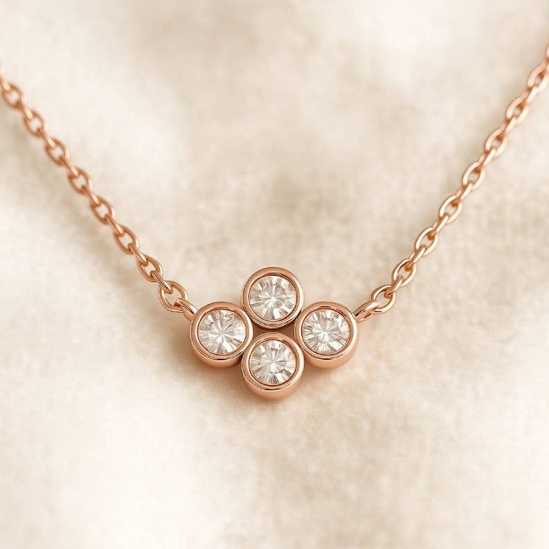 Rose gold necklace with three circular gemstones on a beige background