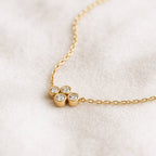 Gold necklace with three diamond-like stones on a white background