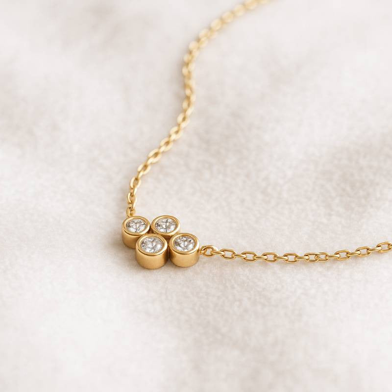 Gold necklace with three diamond-like stones on a white background