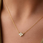Gold necklace with a clover-shaped pendant on a person wearing a green top.