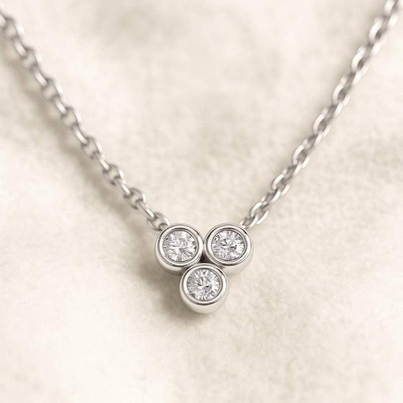 necklace with three round diamonds on a light beige background