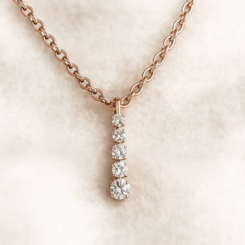 Rose gold necklace with a diamond pendant on a soft beige background