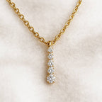 Gold necklace with a diamond pendant on a light beige background
