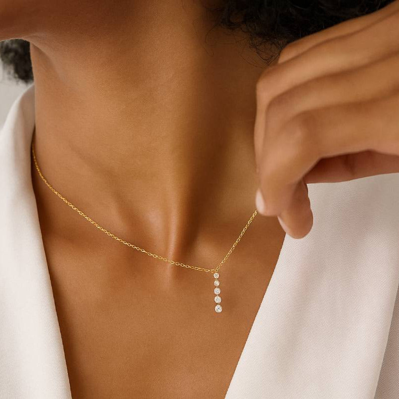 Close-up of a person wearing a delicate gold necklace with a small pendant.