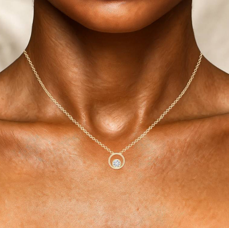 Gold necklace with a blue gemstone pendant on a person's neck