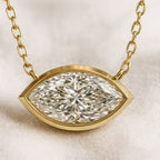 Gold necklace with a diamond pendant on a beige background