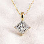 Gold necklace with a square-cut diamond pendant on a light background