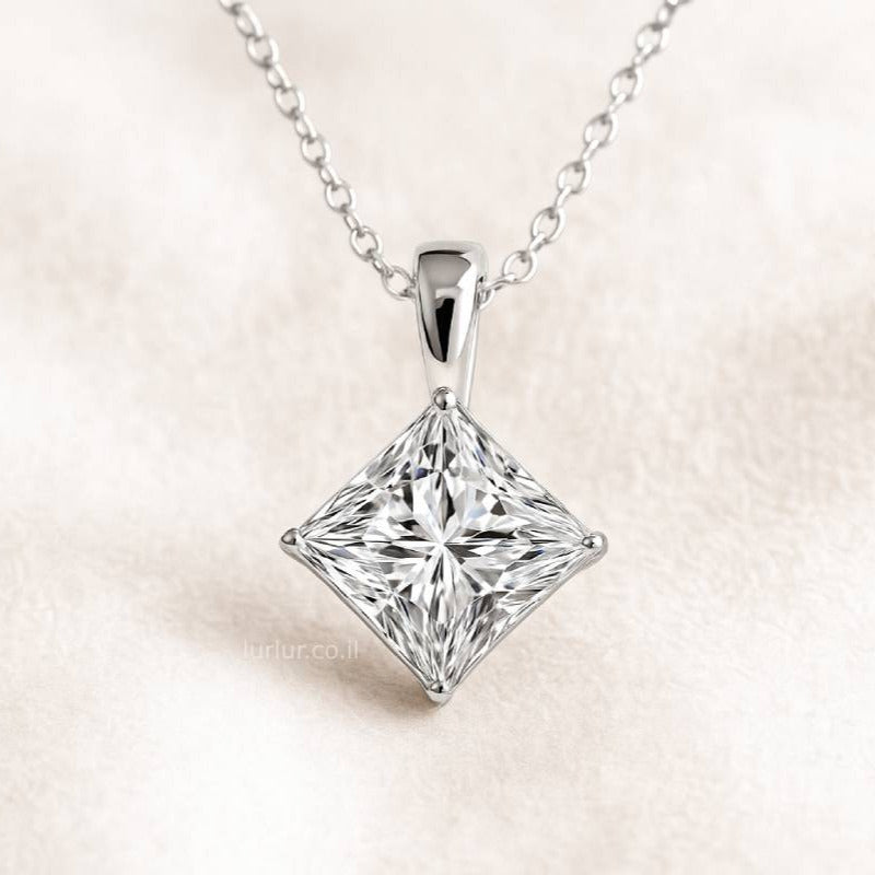 Princess cut diamond pendant on a chain against a light background