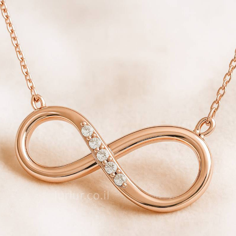 Rose gold infinity necklace with small diamonds on a beige background