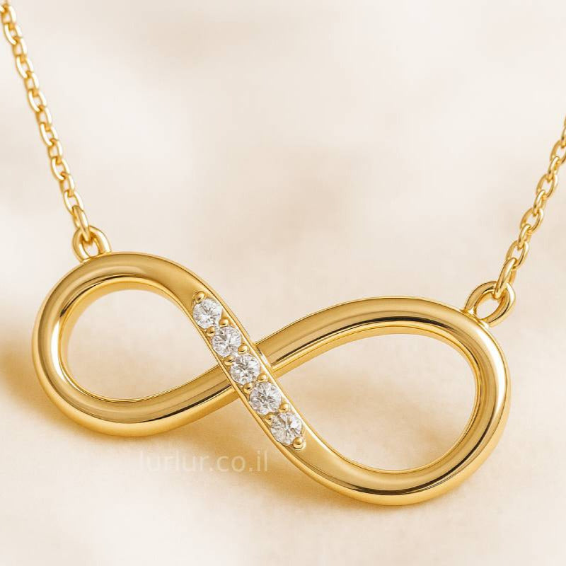Gold infinity necklace with small diamonds on a beige background