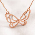 Rose gold butterfly necklace with diamonds on a light pink background