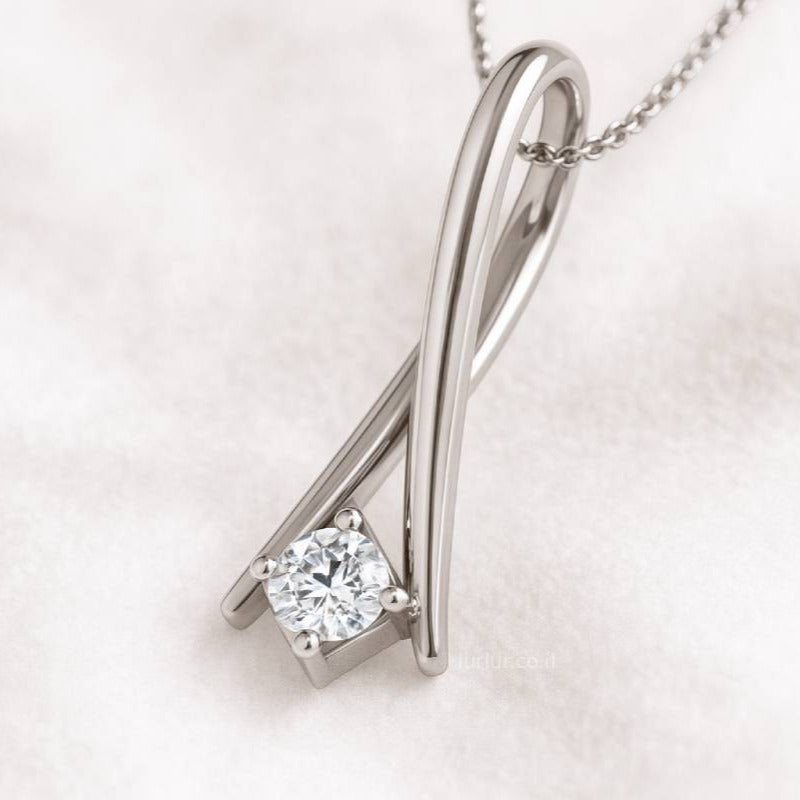 gold pendant with a diamond on a light pink background