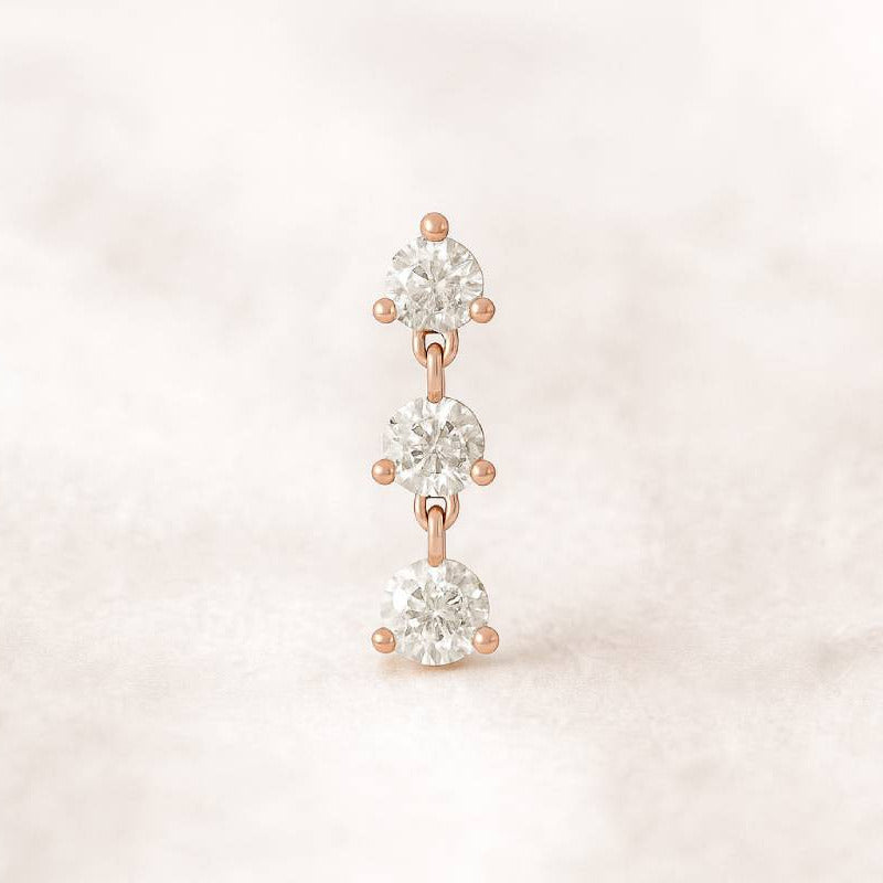 Rose gold earring with clear gemstones on a light pink background