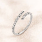 Gold open ring with small diamonds on a light pink background