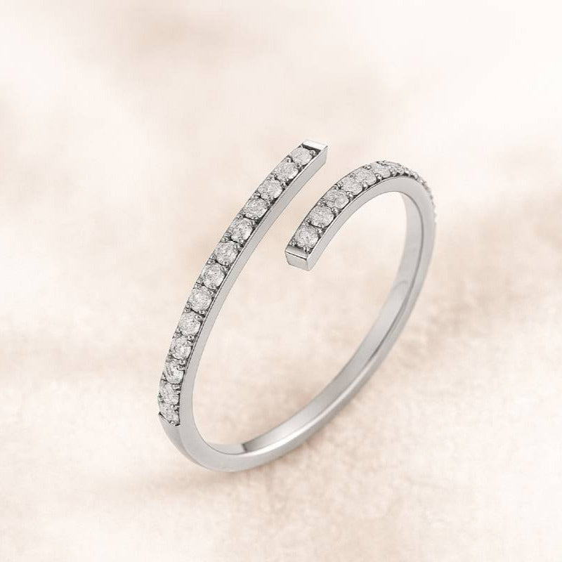 Gold open ring with small diamonds on a light pink background