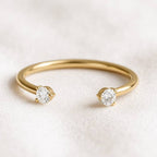 Gold ring with two diamonds on a light background