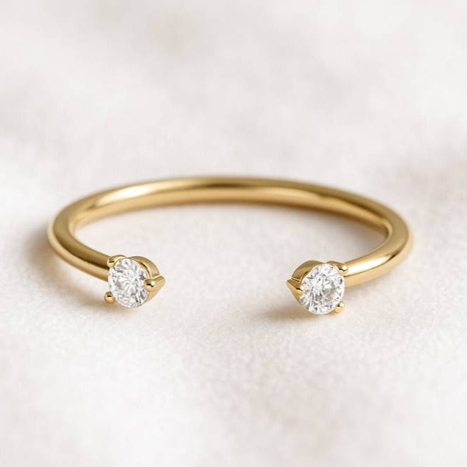 Gold ring with two diamonds on a light background