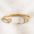 Gold ring with three clear gemstones on a light beige background