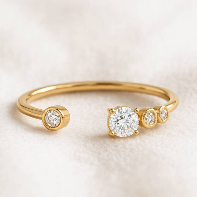 Gold ring with three clear gemstones on a light beige background
