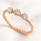 Rose gold ring with three diamonds on a light background