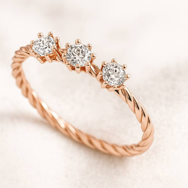 Rose gold ring with three diamonds on a light background