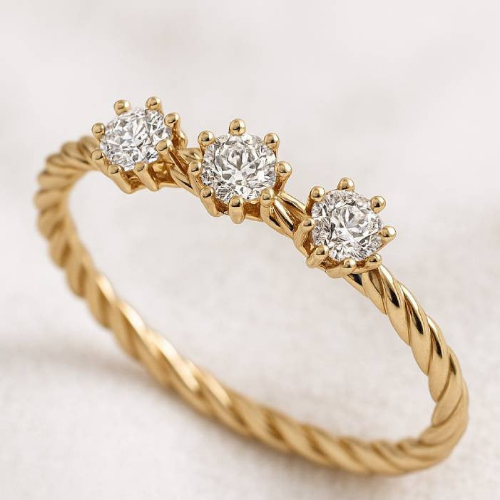 Gold ring with three diamonds on a light background
