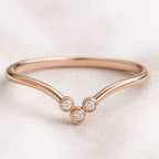 Rose gold ring with three clear gemstones on a light background
