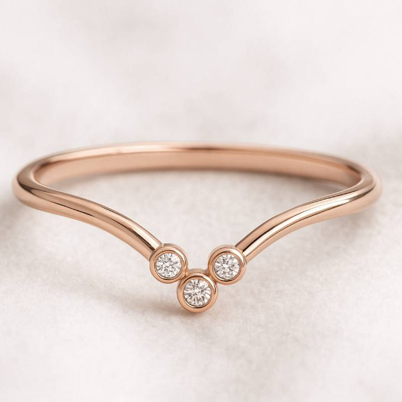 Rose gold ring with three clear gemstones on a light background