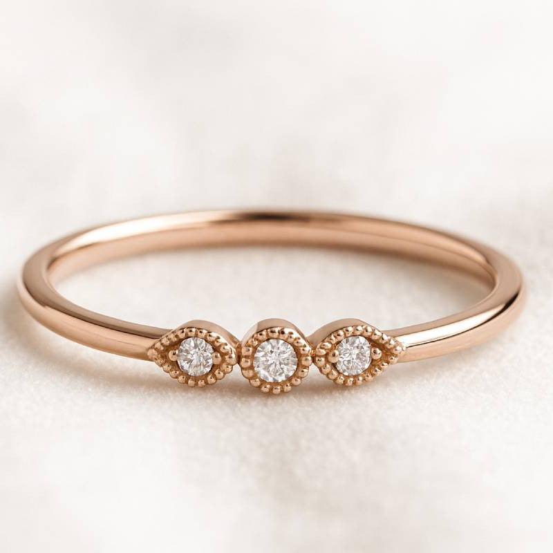 Rose gold ring with three diamonds on a light background