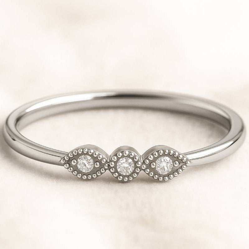 gold ring with three small diamonds on a light beige background