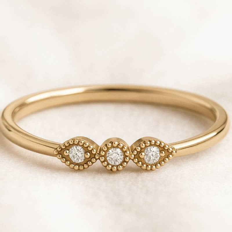 Gold ring with three diamonds on a beige background