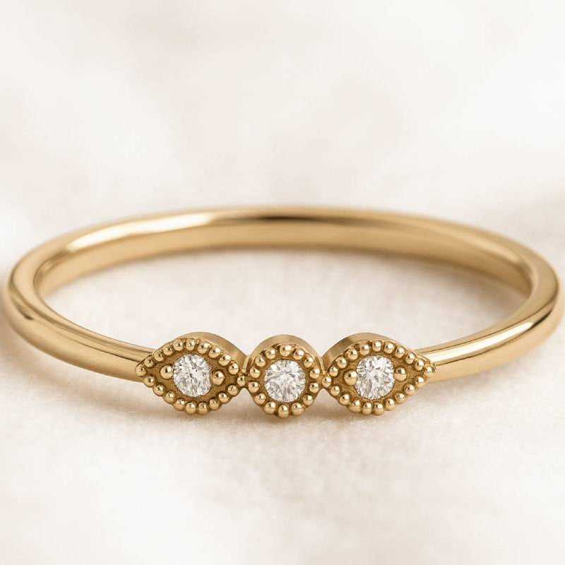 Gold ring with three diamonds on a beige background