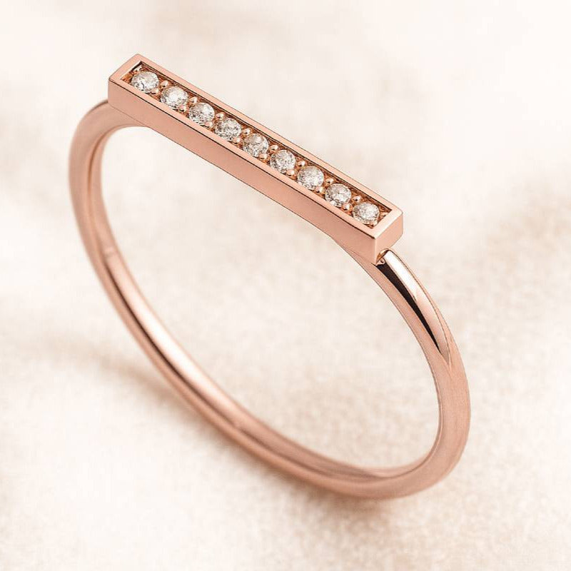 Rose gold ring with small diamonds on a beige background