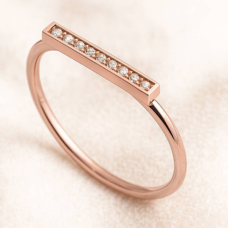 Rose gold ring with small diamonds on a beige background
