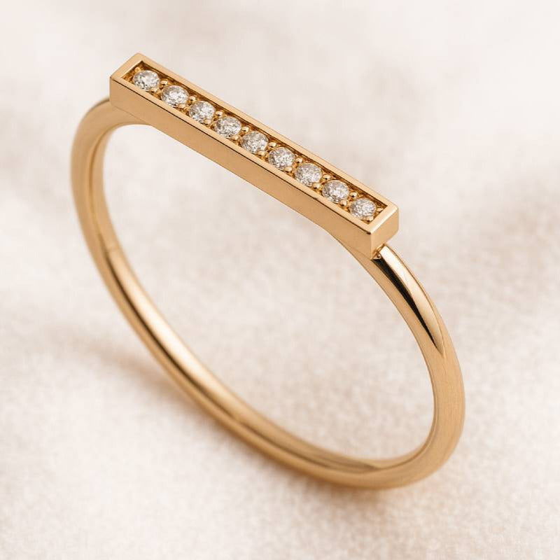Gold ring with small diamonds on a light beige background