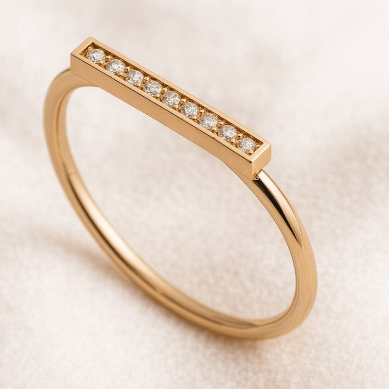 Gold ring with small diamonds on a light beige background