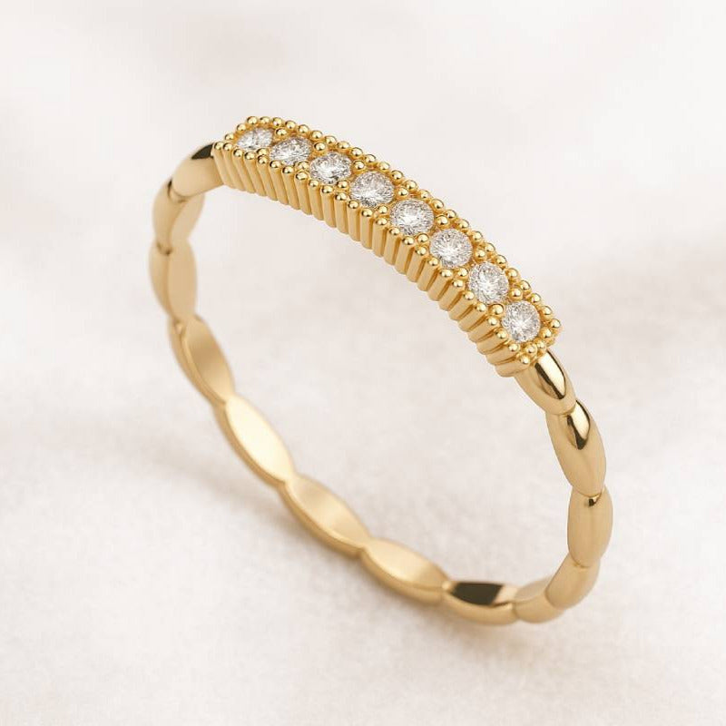 Gold ring with small diamonds on a light beige background