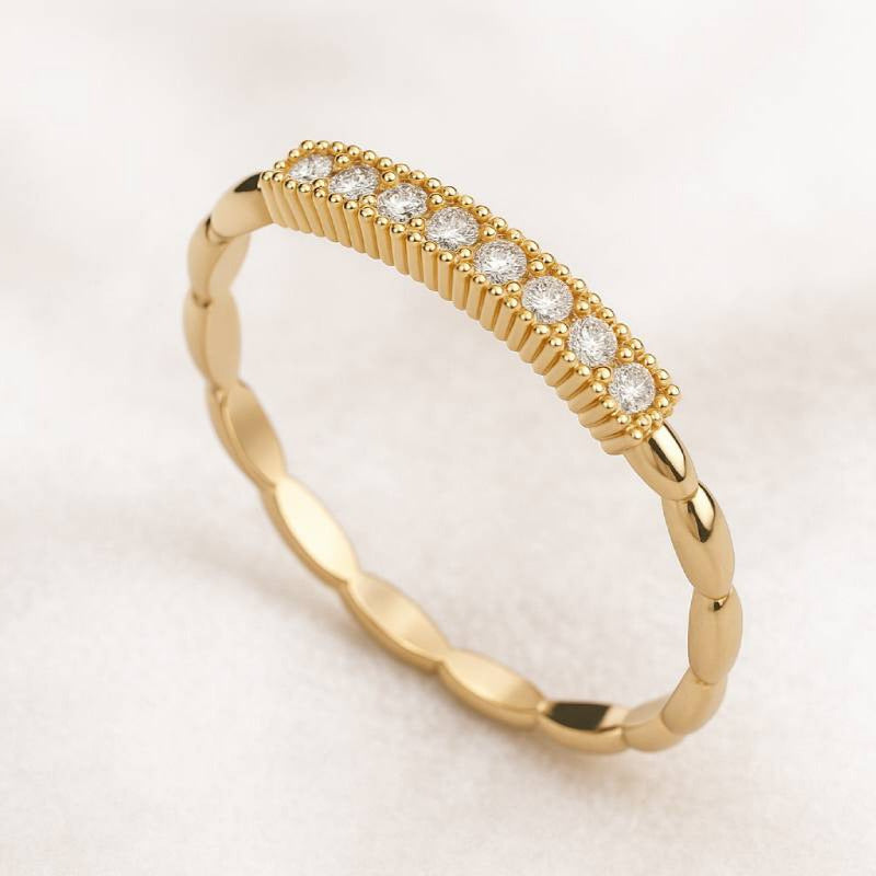 Gold ring with small diamonds on a light beige background