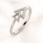 Gold ring with diamond accents on a light pink background