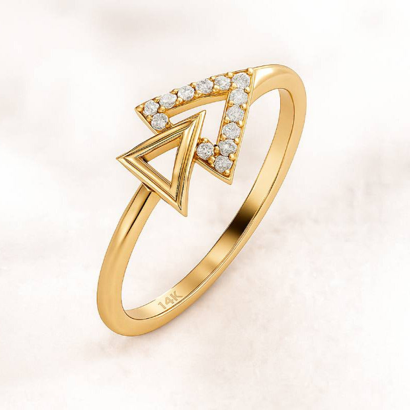 Gold ring with a diamond-encrusted triangle design on a light pink background