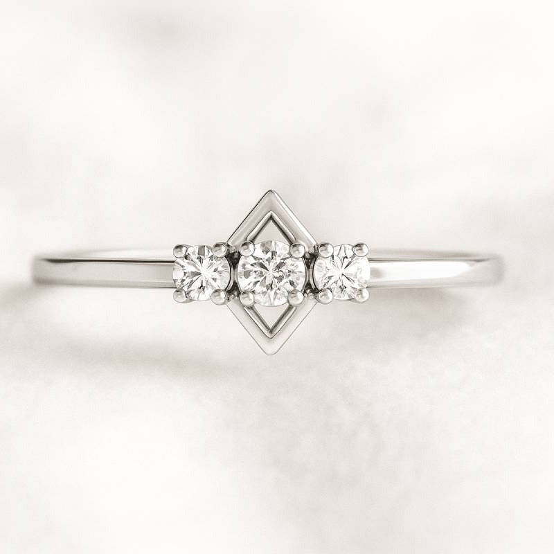 Delicate gold ring with three diamonds on a light background