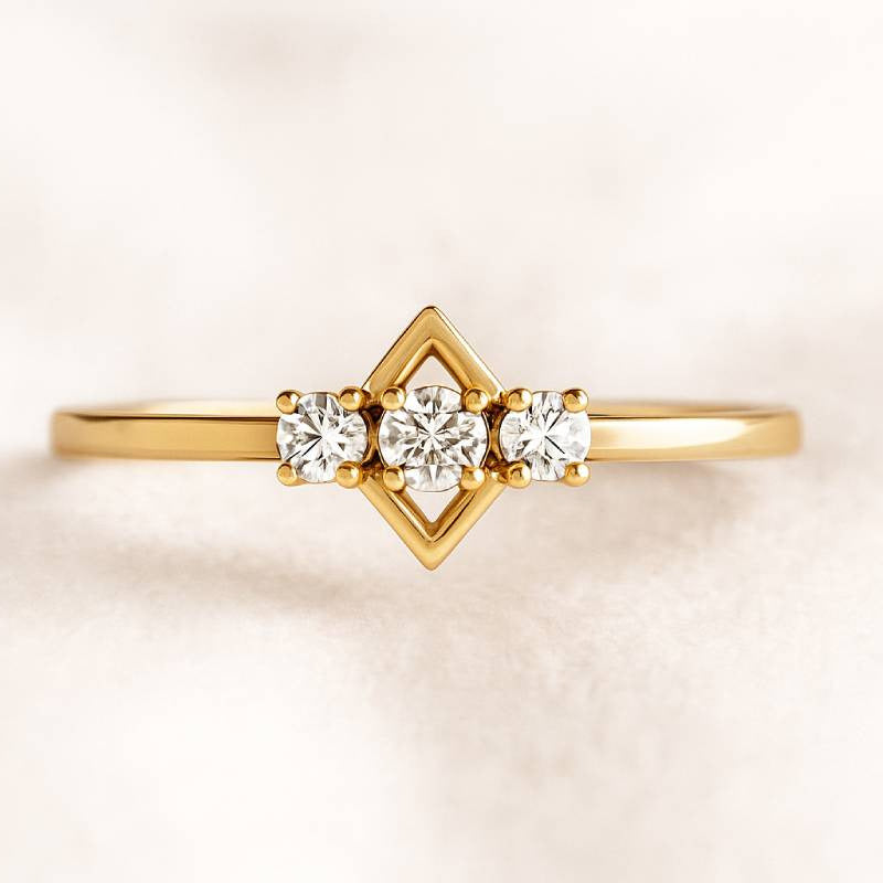 Gold ring with three diamonds on a light beige background