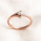 Rose gold ring with a diamond on a light beige background