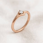 Rose gold ring with a diamond on a light beige background