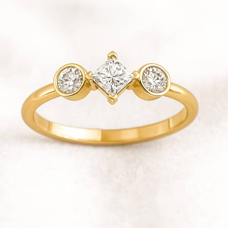 Gold ring with three diamonds on a light pink background